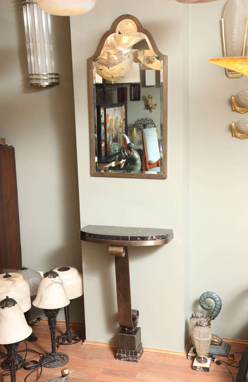 A French Art Deco console table attributed to Raymond Subes, with scrolling leg and portoro gold marble top, together with a tall piriform beveled mirror, created circa 1930s.