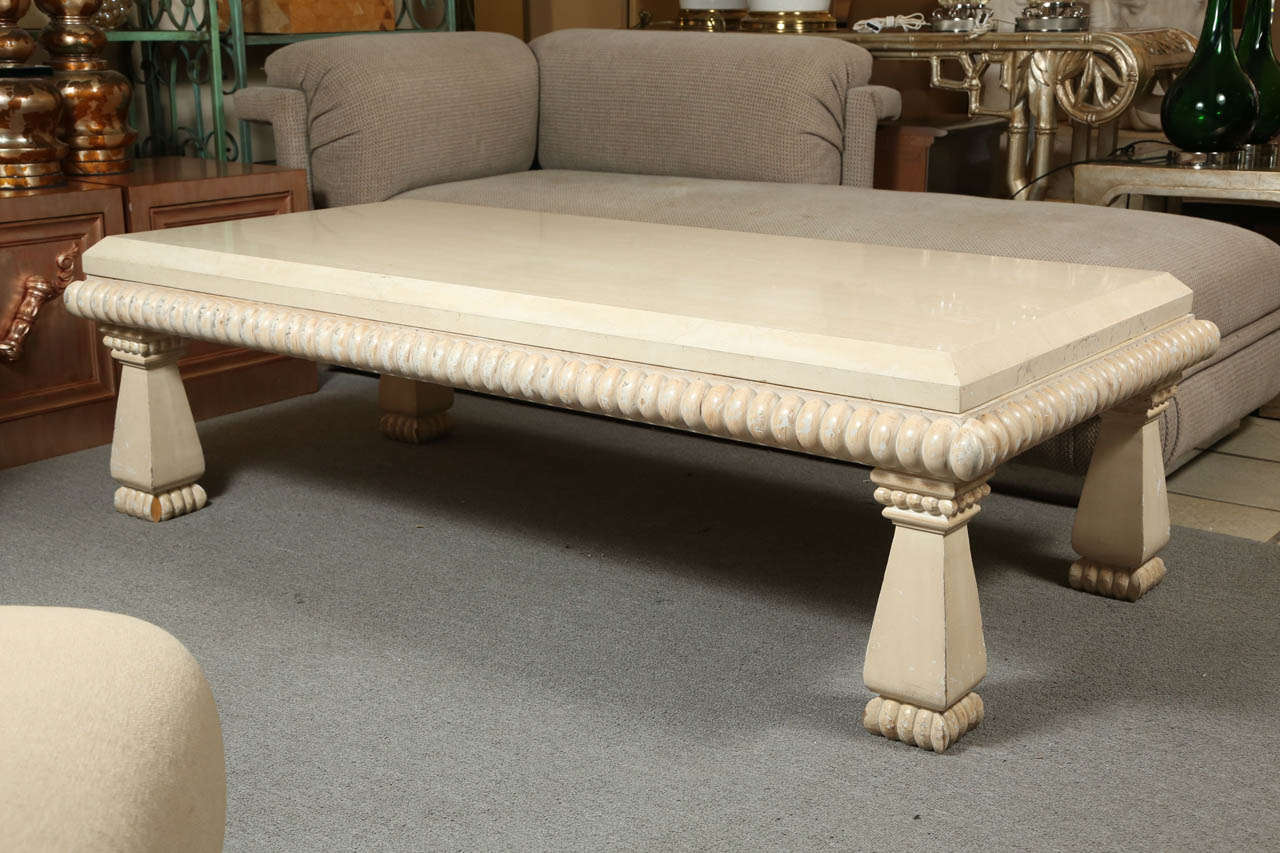 Carved wood coffee table with a polished travertine top by Kreiss.   The wood has a pale distressed natural finish