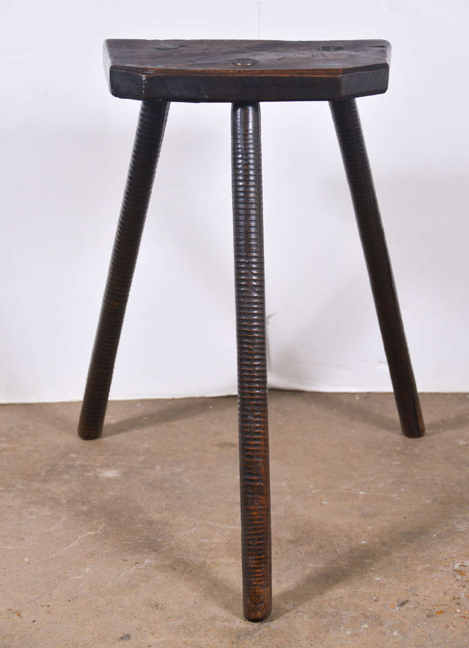 19th century Elm cutler's stool from England. These Primitive looking three-legged stools with ridges up the legs are what the workers would sit at their individual work stations in factories such as Sheffield's cutlery and flatware company, hence