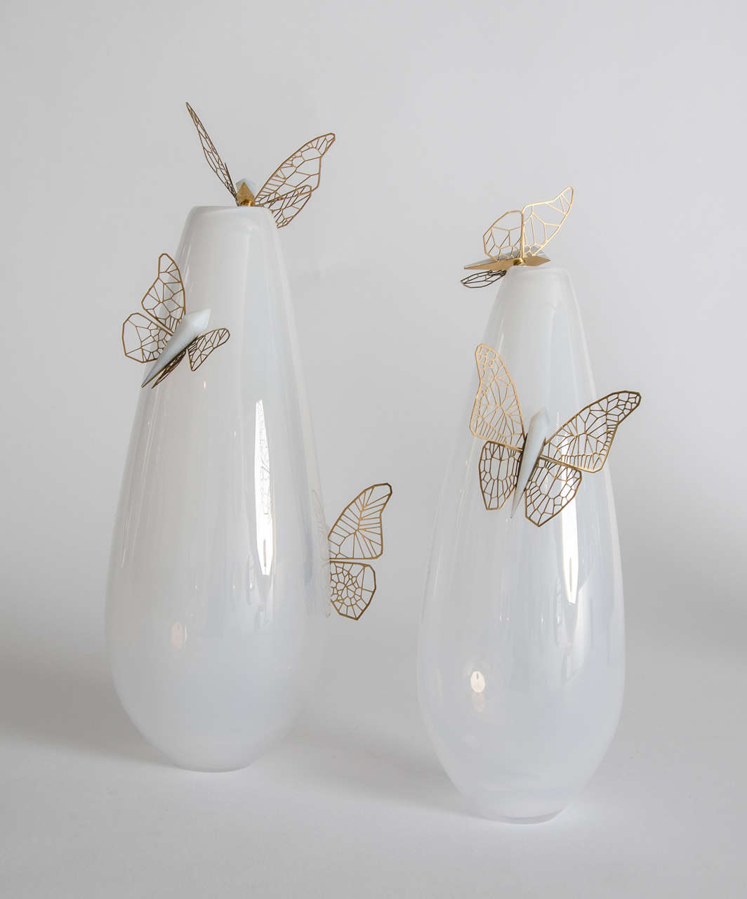 Hanne Enemark's excelling at mixing materials as demonstrated with this piece. 

Thin gold-plated etched steel butterflies, each with a different wing pattern and a white glass crystal shaped cut-glass body, sitting perched on the white
