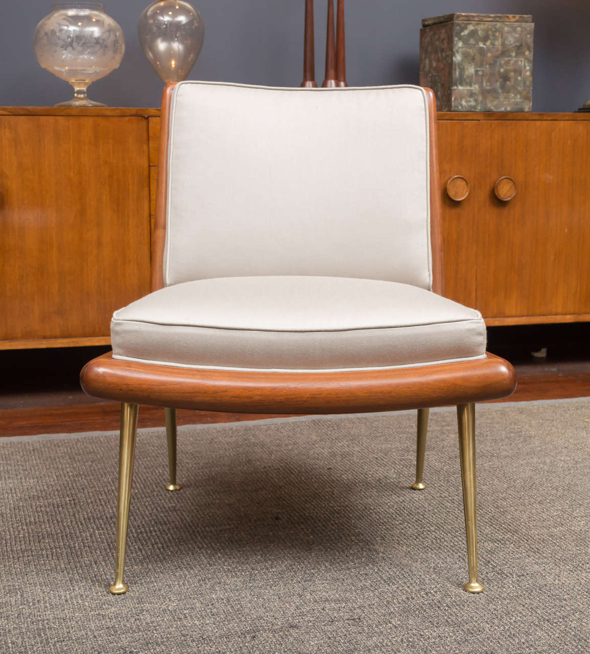 Elegant and refined lounge chair designed by T.H. Robsjohn-Gibbings for Widdicomb Furniture Co. 
Sculpted solid walnut frame supported on tapering brass legs with new upholstery.