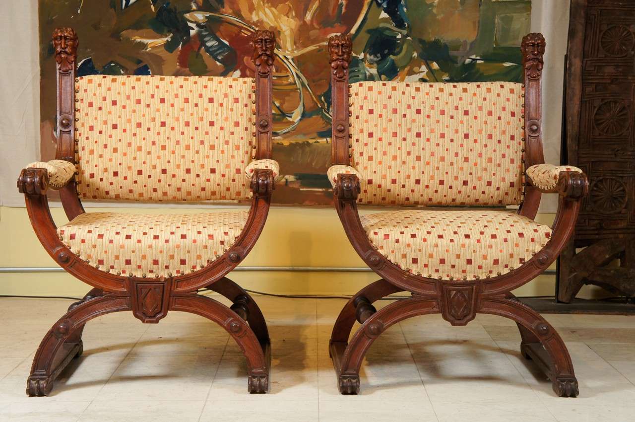 Pair of baronial armchairs in the renaissance-style  with carved head finials and scrolled arms in oak, early 20th century