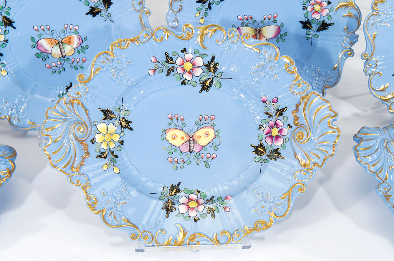 This early 19th Century dessert service was made by John Ridgways, ca. 1802 and features a molded and relief plate with all over blue glaze creating a dramatic contrast to the hand painted butterfly centers. Each plate is uniquely decorated and the
