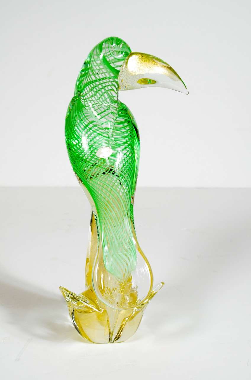 This spectacular Mid-Century hand blown Murano glass tropical bird  in brilliant green atop a stylized branch with 24K gold flecks in the beak and branch.