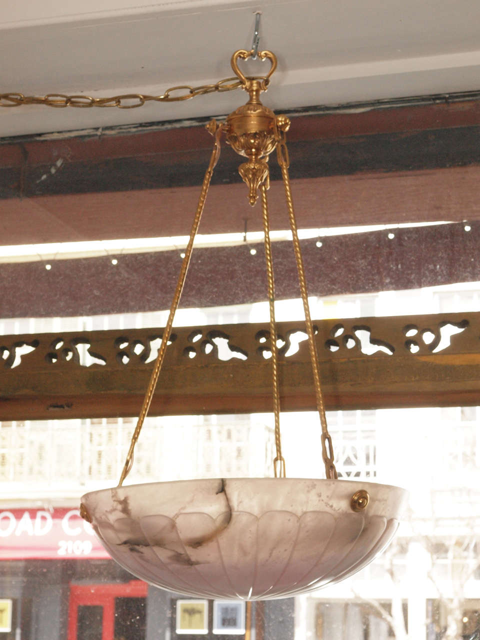 Elegantly classical carved alabaster chandelier suspended from a handsomely  detailed brass chain.