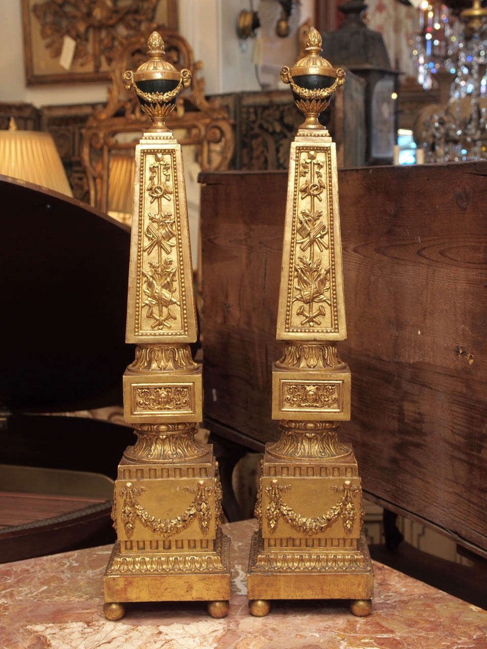 Pair of 18th c. Italian Luigi XVI Gilt Wood Decorated Obelisk with ovoid shaped finials mounted with garland and rams heads all surmounted with an acorn finial.
The obelisk decorated with carved war related musical instruments and foliate