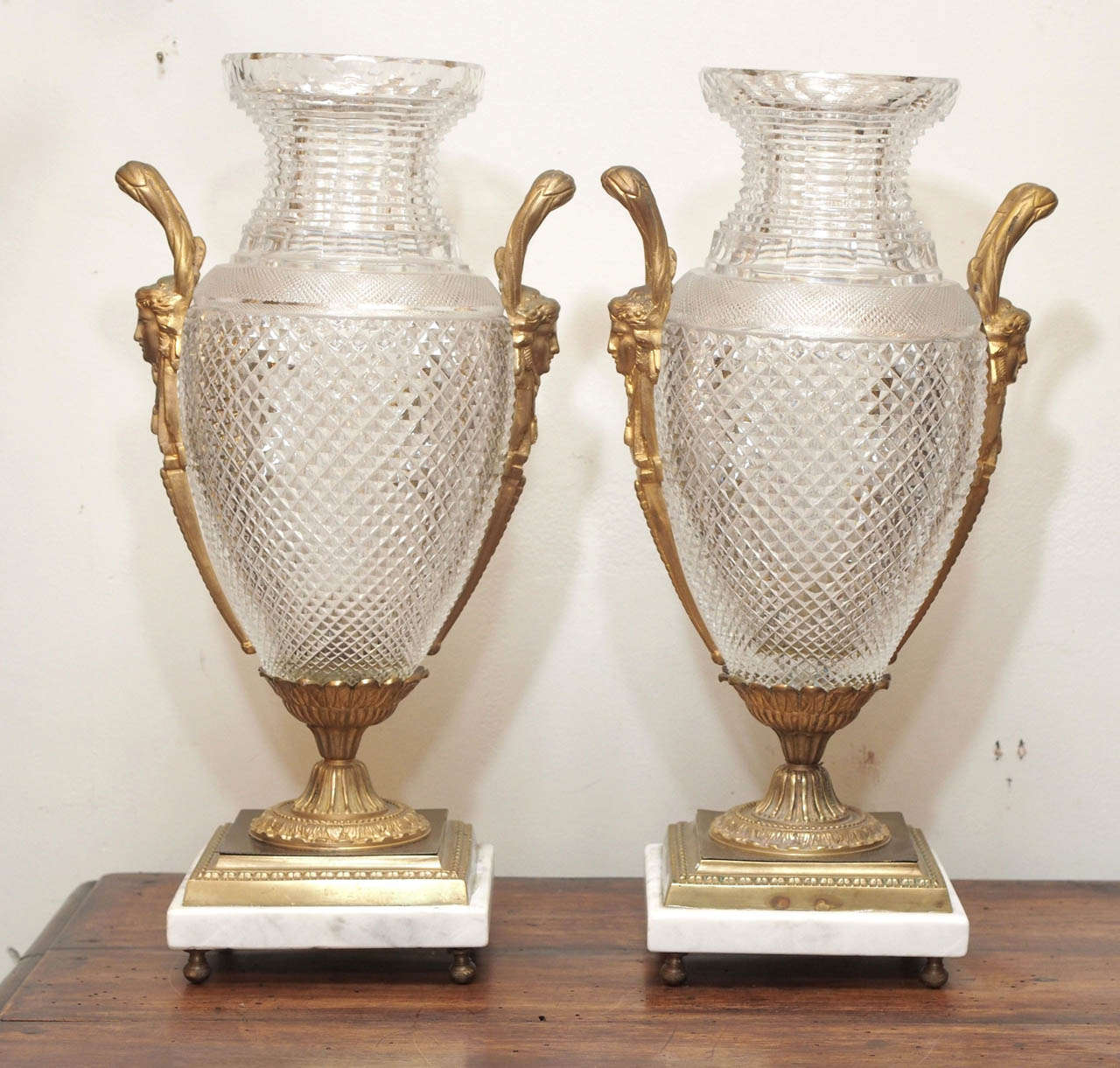 Pair of Cut Crystal Bacarrat Vases with gilt bronze mounts 19th c. later carrera marble bases on bronze ball feet. 
These have been mounted as lamps in the past and then unwired for vases. 
The bronze bases have been drilled (see photo) 
These
