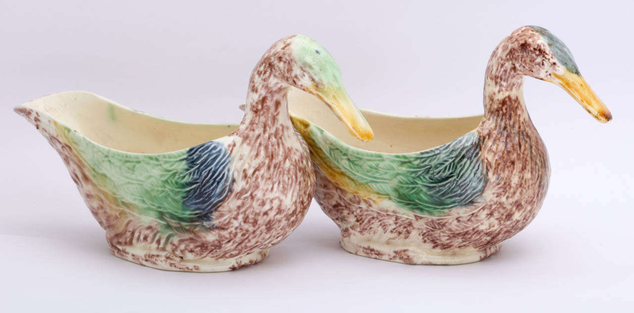 A rare and fine pair of English creamware pottery duck sauceboats decorated in underglaze colors of yellow, green blue and brown