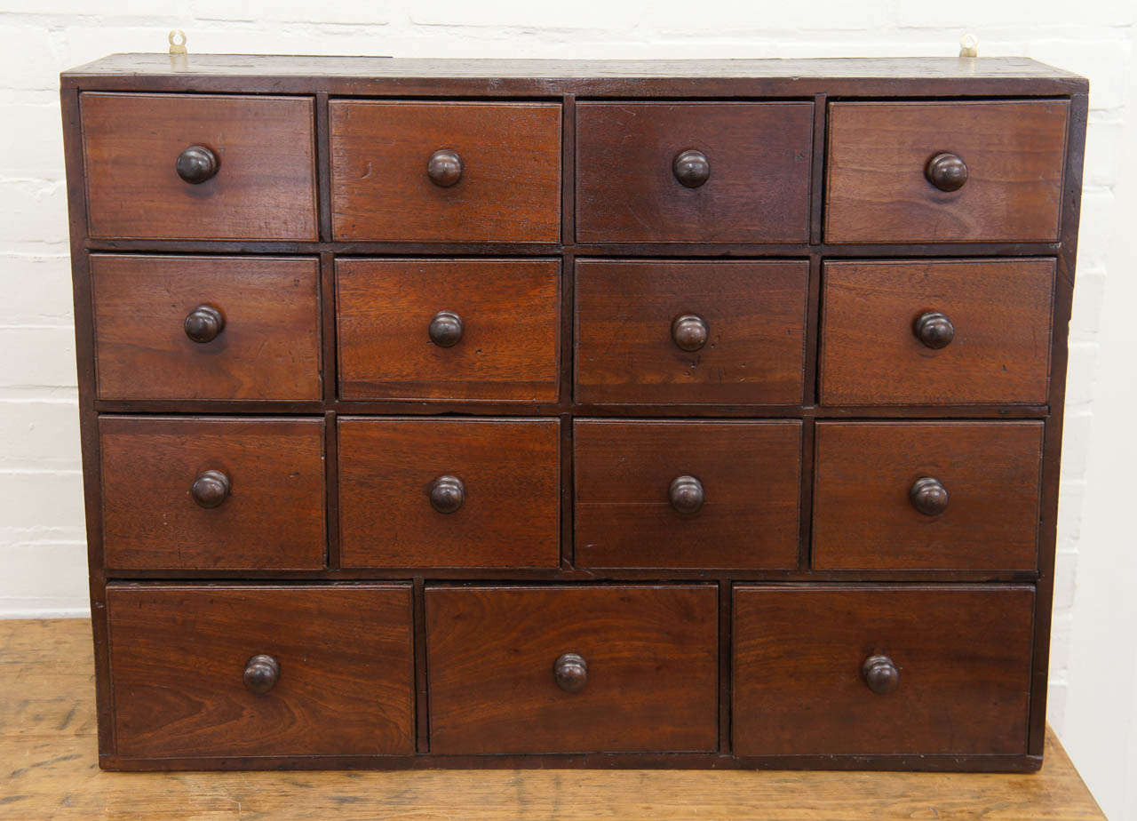 This delightful little bank of spice drawers is from France, circa 1880. It has three rows of four small drawers and below them are three larger drawers, all with wood pulls. The patina on this piece is beautiful. It comes with hooks to hang on the