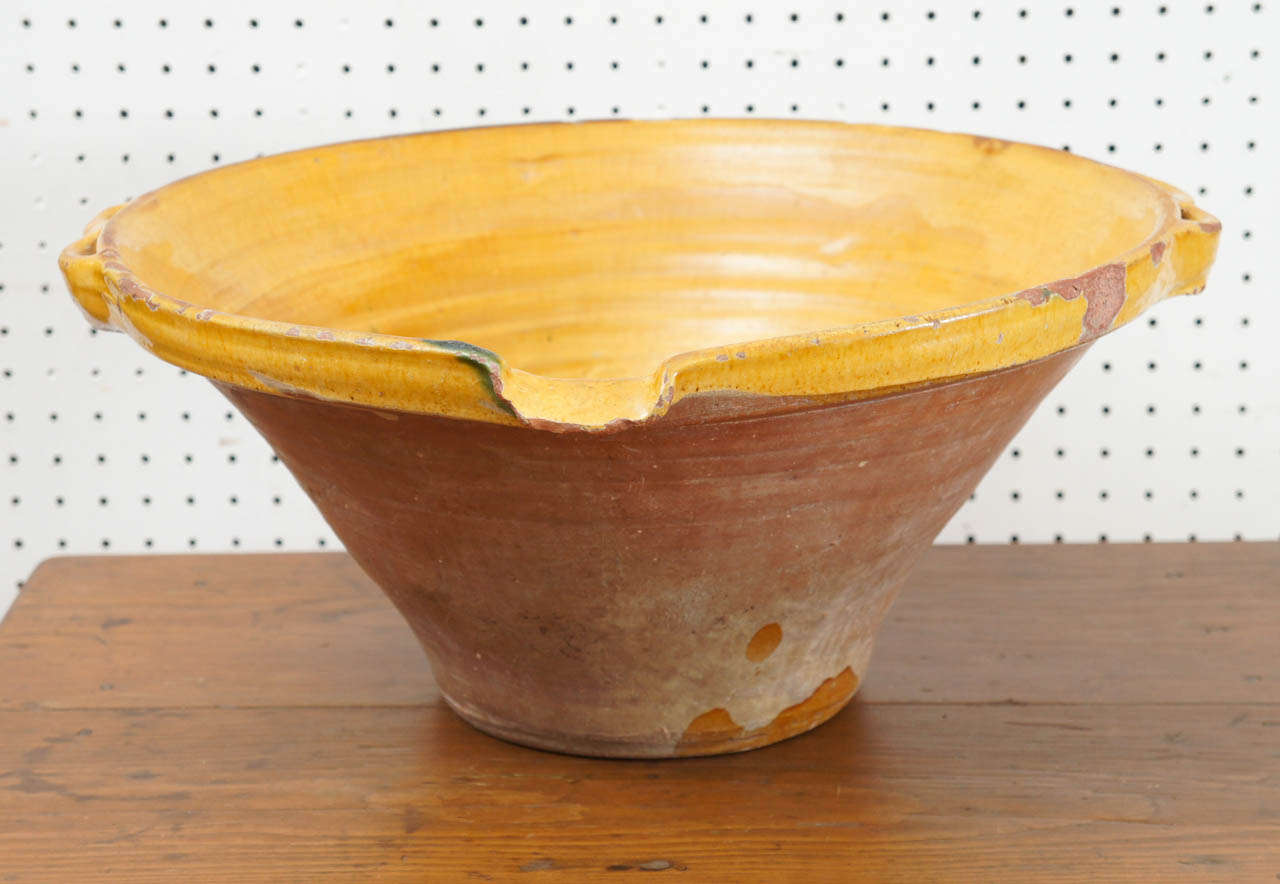 Glazed a wonderful mustard color on its interior, this huge French dairy bowl is quite the centerpiece. Its color is fabulous. It has great double folded handles and a spout for pouring. This piece would look wonderful as a center piece on a dining