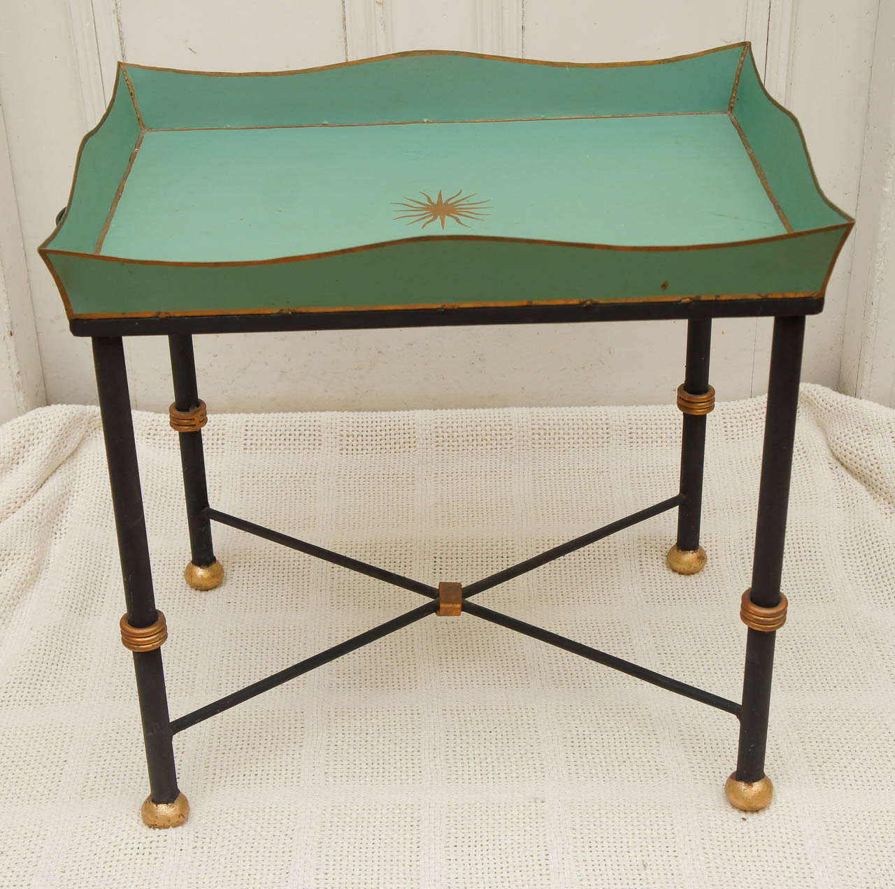 Green tole tray with gold decoration on cast iron base with gold knobs and iron handles on either side of tray for carrying. Briger Design. Gold sunburst star in the center of tray.   Height measurement is to the rim of the tray.  Nice size and easy