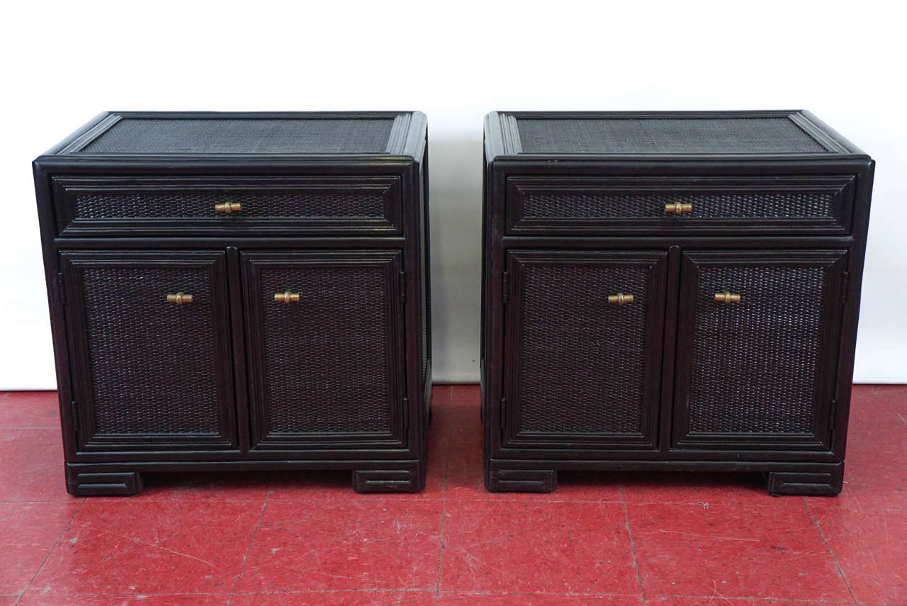 These nightstands, bedside tables or end tables are black lacquered beechwood with inset rattan panels, single drawers and brass pulls.