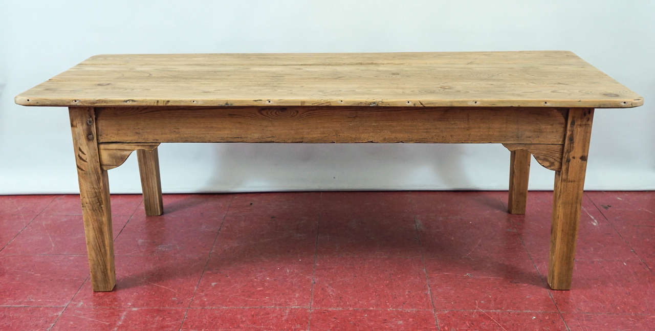 Reduced in height from an antique pine farm table, this rustic farm coffee table has corner brackets for added charm and support.