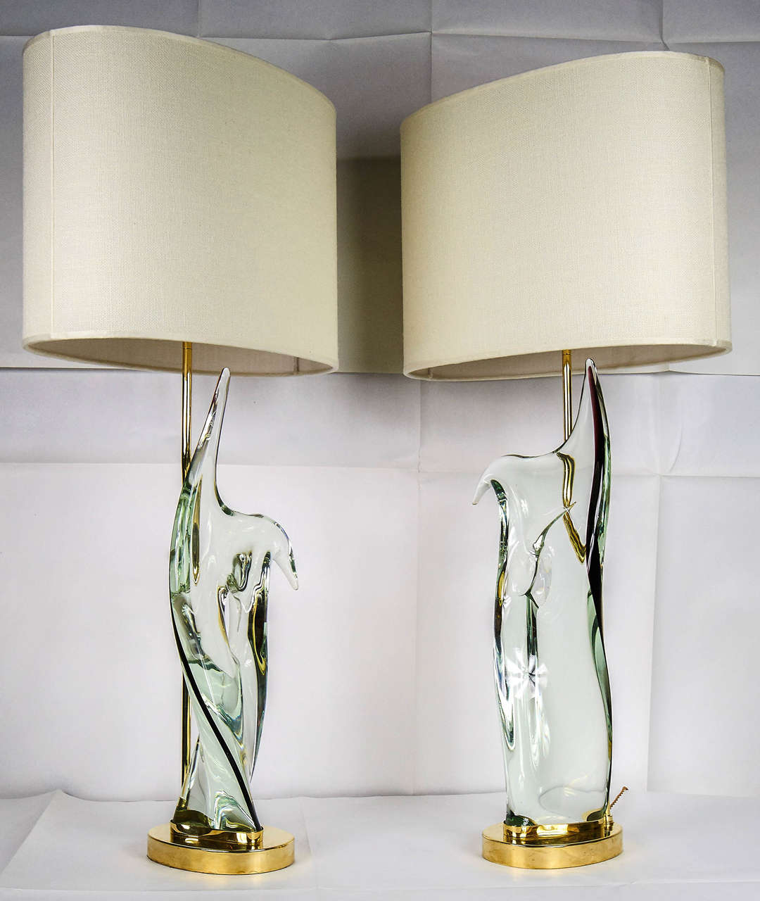 Pair of table lamps, Murano handmade informal sculpture transparent glass with black pasta of glass line on one side.
The informal shape with a hole is really representative of the 1950s.
Brass structure made created individually for each glass