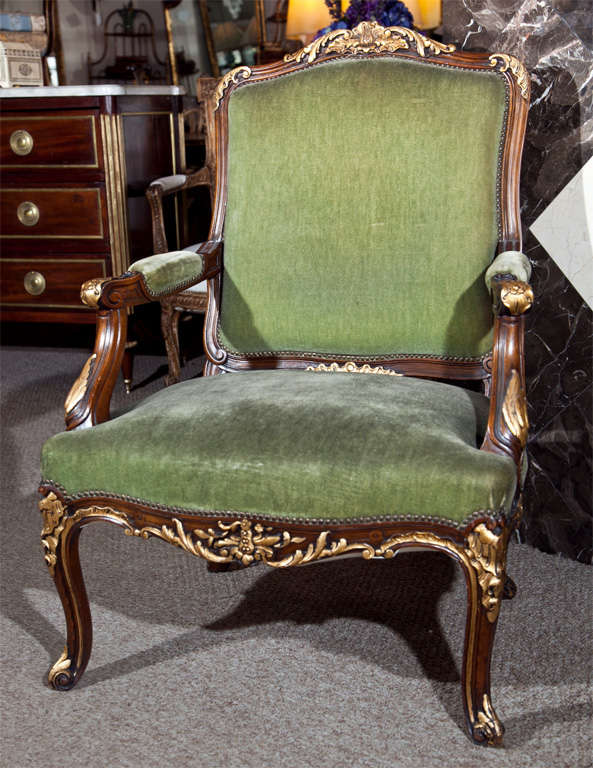 Pair of French Louis XV Style walnut armchairs, 20th century, the top with parcel-gilt foliate crest, padded arms and seat, raised on cabriole legs.