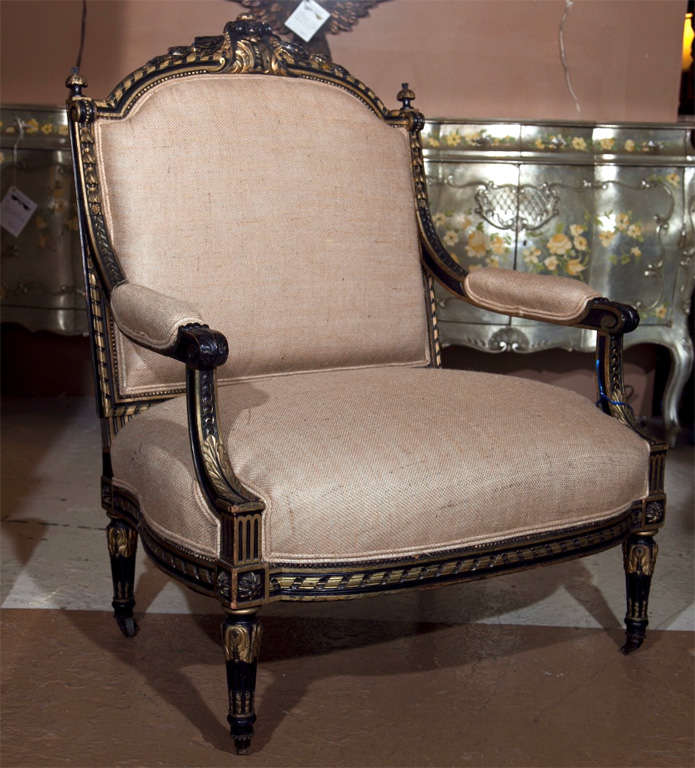 French Louis XVI style fauteuil a la reine, circa 1950s, overall ebonized and parcel-gilt upholstered in burlap, raised on fluted bulbous legs ending in casters. By Jansen.
