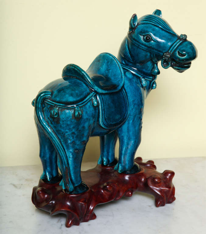 Antique Chinese porcelain glazed figure of a finely saddled and equipped standing horse with his ears upright and his head turned to the right, on a custom wood stand, circa 1900.