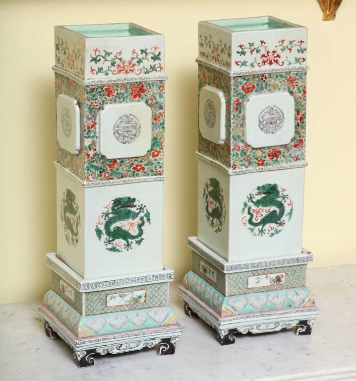 Pair of tall square Chinese porcelain vases decorated in a famille verte palette with dragons and flowers in three sections, supported on separate stepped bases, Chinese, circa 1850.