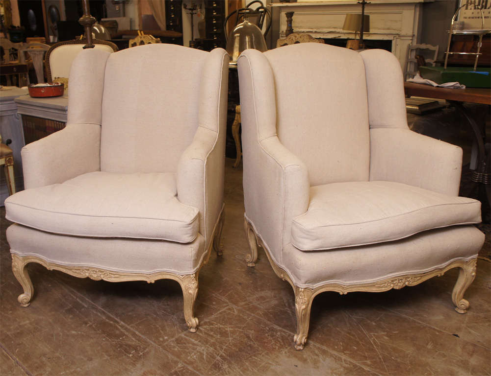 Louis XV style wing armchair in pickled oak, cabriole feet, undulating top crests; newly upholstered in linen.  
Great frame and a very comfortable chair to relax and read a book in.