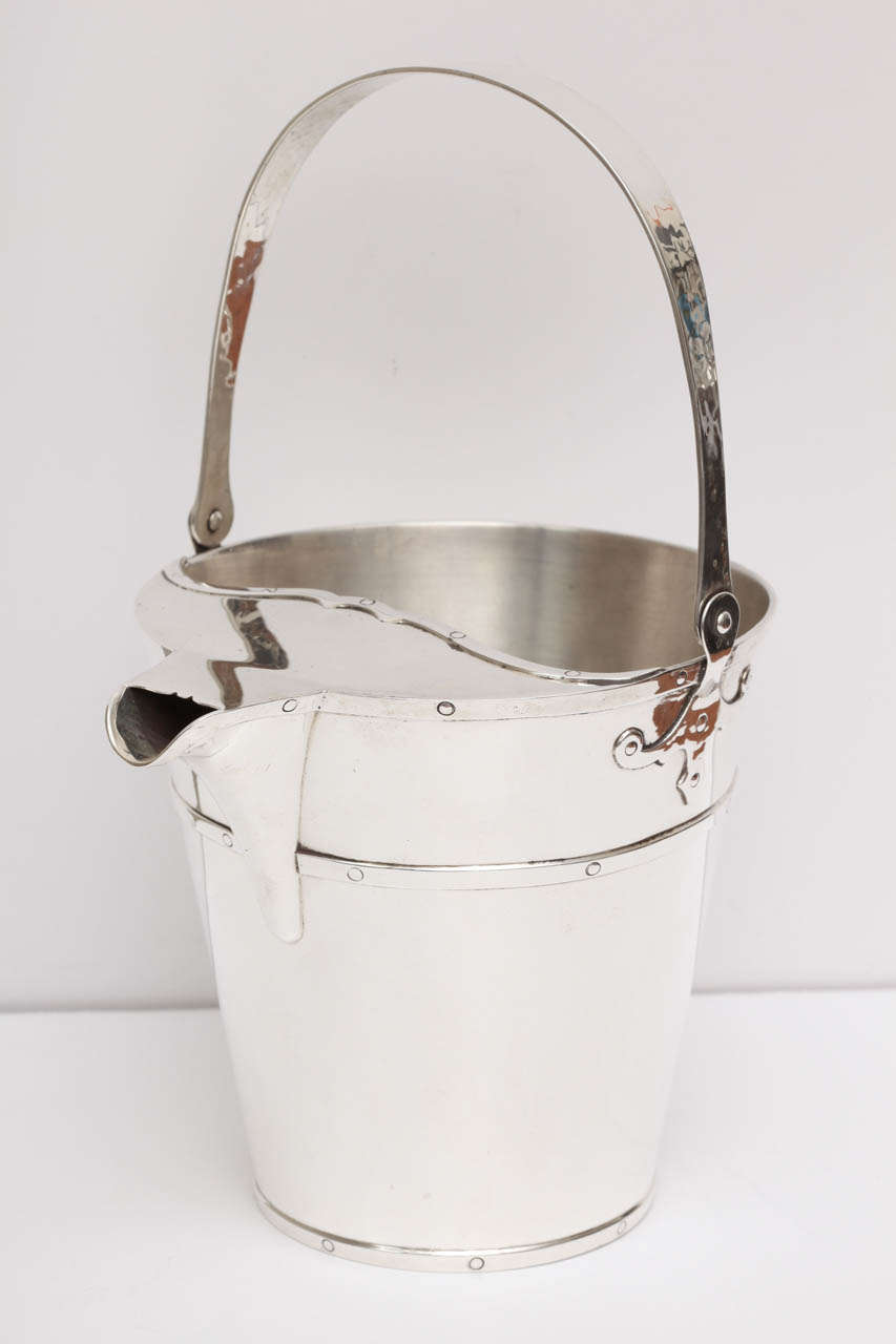 An unusual and early piece by Gorham, this novelty piece is a cocktail mixing bucket with built in strainer and pouring spout. Designed as a pail complete with an articulated handle. It has beautiful decorative details where the handles connect to