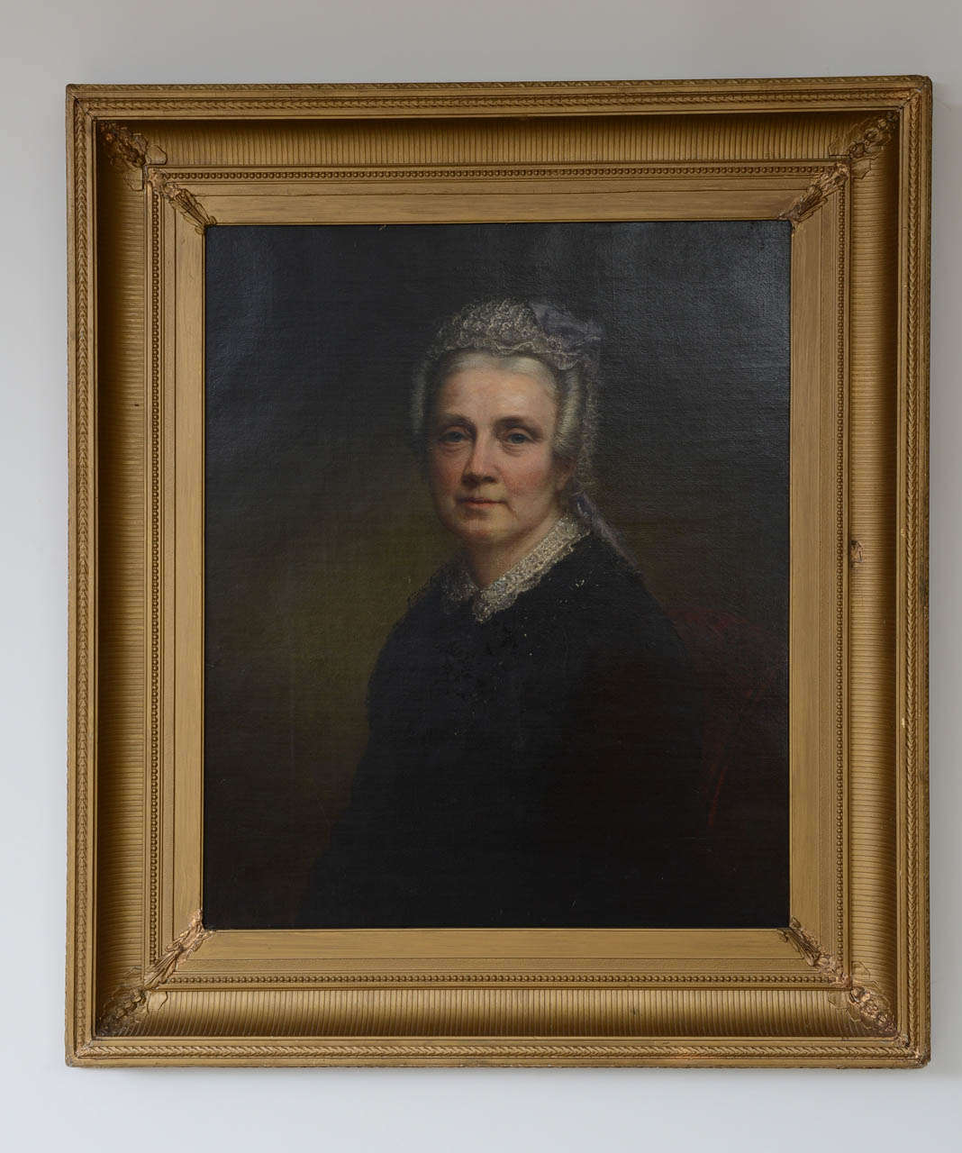 Waist-length portrait of a elderly woman wearing lace collared black dress and a wig with single curls and a lace cap in her hair.  She sits on a wine colored upholstered straight back chair.  Information on reverse: 