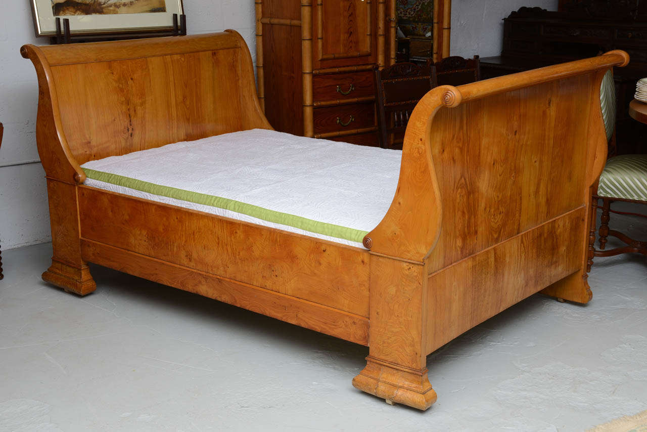Louis Philippe sleigh bed with outswept paneled head and foot boards joined by side rails. Bed is fitted with a custom platform and covered in an off-white upholstery fabric, trimmed with green ribbon. Original restored finish.