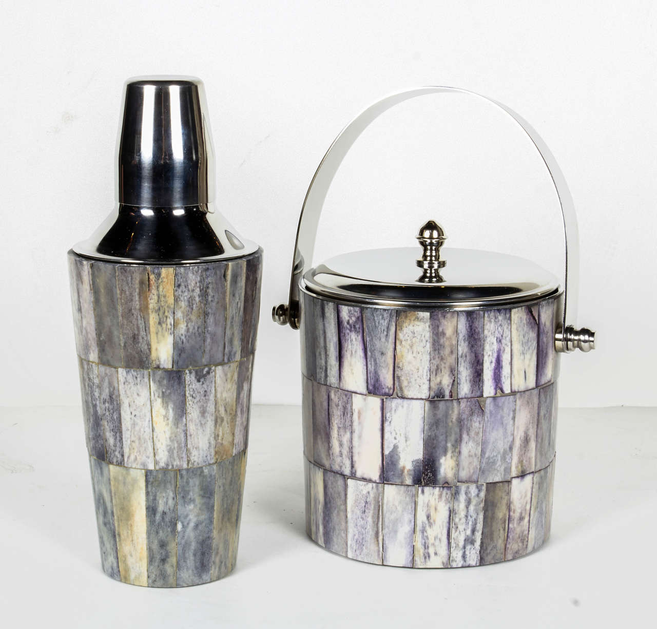 Uber chic barware set in tesselated bone tiles and polished chrome. Bone tiles have varient hues of grey, ivory, and slight shades of tan. The set consists of a matching cocktail shaker and ice bucket (or wine cooler) with chrome metal tongs.  Great