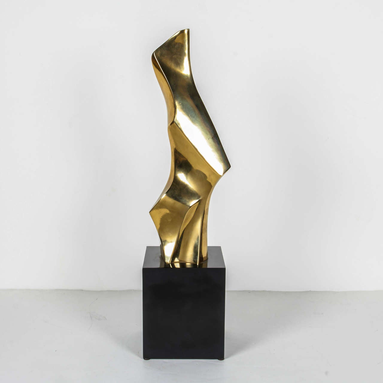 Brutalist abstract sculpture with amorphous form. The sculpture consists of polished brass free-form metal with black enameled cast metal pedestal base.
