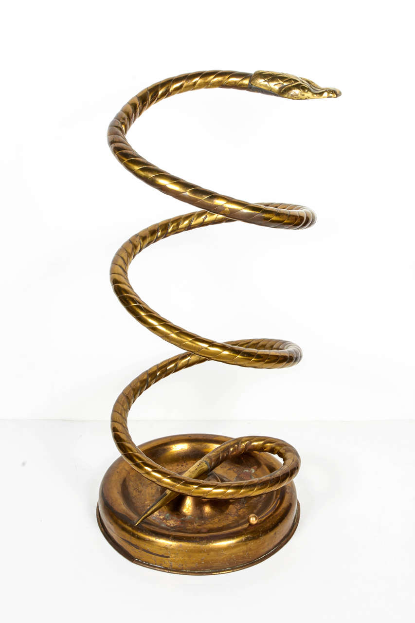 Rare and elegant 1920s brass cobra umbrella stand. Highly stylized coil form with hand-forged designs and circular base detail. The umbrella stand has a lot of patina consistent with age and use. This item is for the collector that appreciates