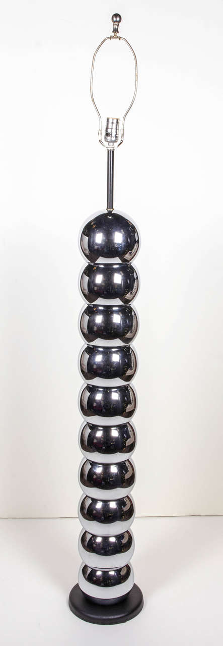 Mid-century modern floor lamp comprised of stacked globes or orbs in polished chrome metal. Highly stylized with circular black enameled metal base and fittings. Includes custom linen drum lampshade in off-white.