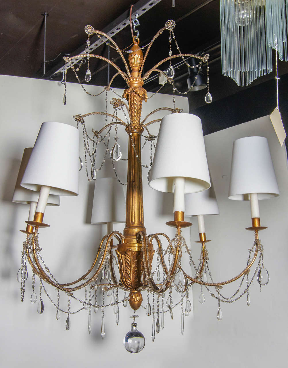 Glamorous chandelier with 22-karart gold leafing over hand-carved wood. The chandelier features six scrolled arms and has stylized acanthus leaf designs throughout. The chandelier features hanging cut crystals pendants and crystal beading along with