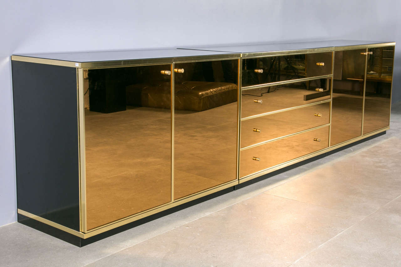 Can be use as a large credenza or sideboard but can be separate in a chest of drawers and two sideboards. Amber glass, gilt brass and black glass top.