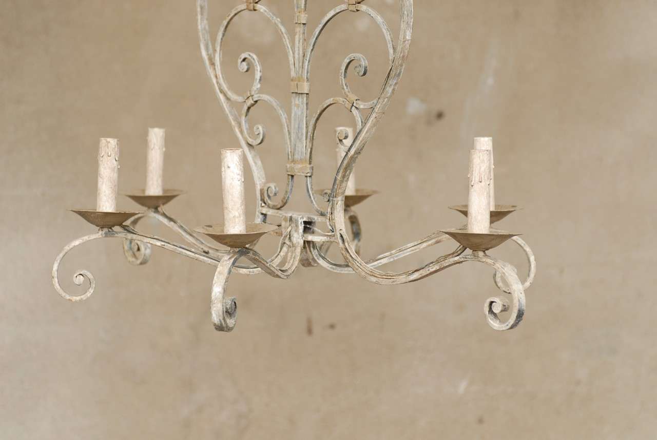 This vintage six-light painted iron chandelier from the 1960s features a central two-dimensional body made of C-scrolls of various sizes joining a central flame looking beam. This piece is very symmetrical and harmonious with the subtlety of the