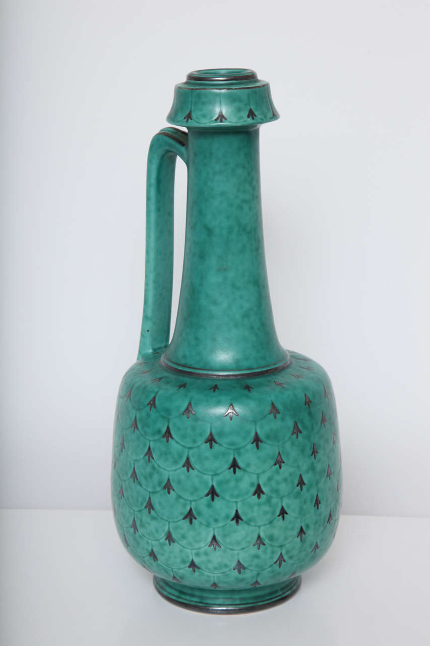 Stoneware piece in typical green Argenta glaze with silver inlaid designs. Signed at bottom, made by Gustavsberg.
