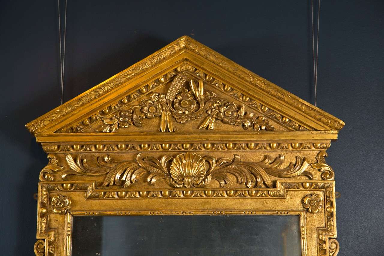 An English George II period pedimented and giltwood mirror.  The mirror glass is circa 1800.