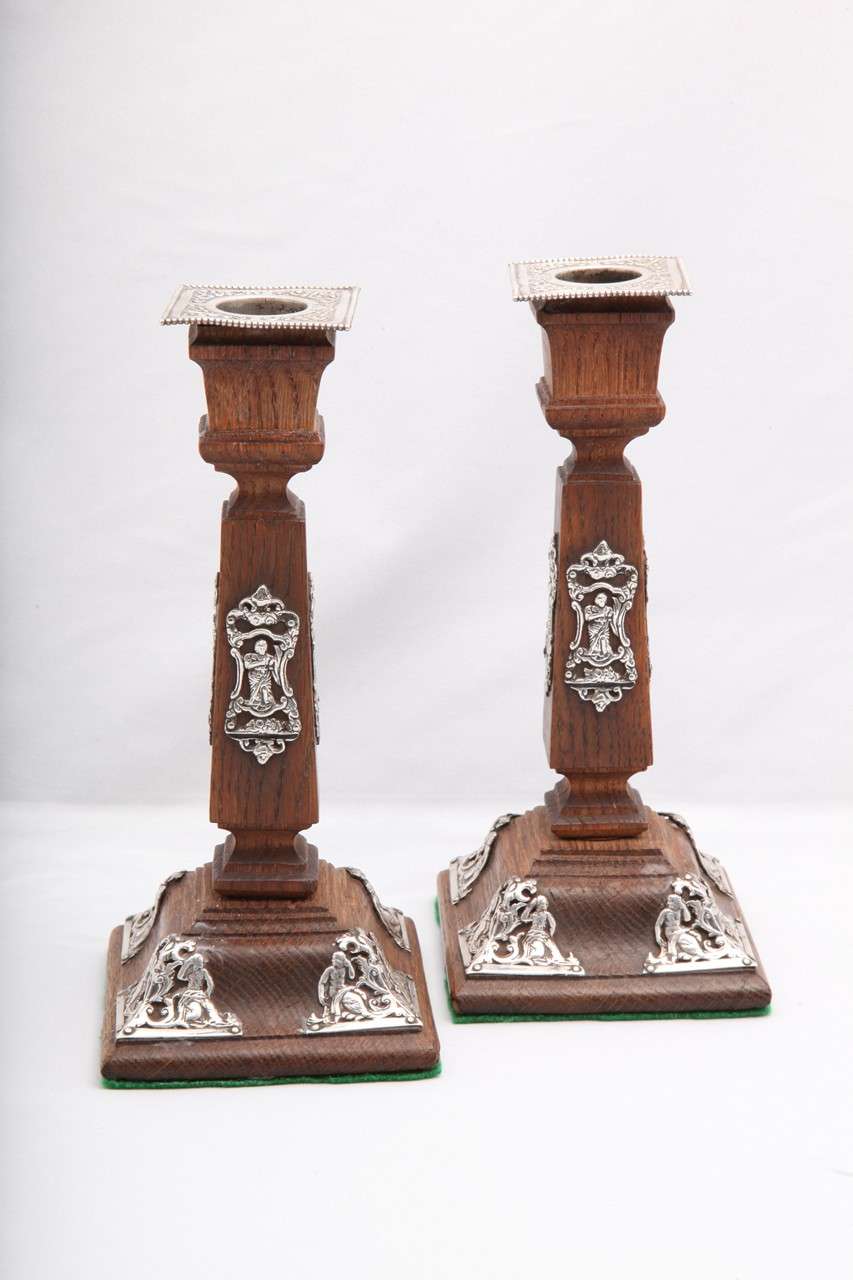 Pair  of Victorian, sterling silver-mounted oak candlesticks, London, year-hallmarked for 1885, John Batson - maker. Each candlestick measures 7 3/4 inches high x 3 1/2 inches wide (at widest point) x 3 1/2 inches deep (at deepest point). Each