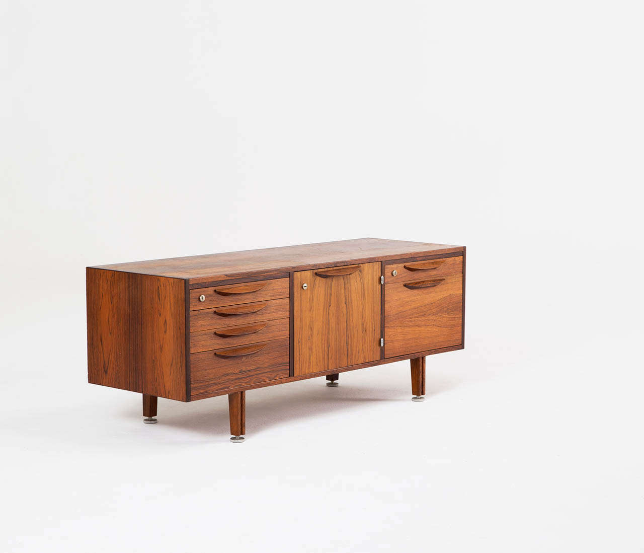 Credenza, rosewood, Denmark, 1960s.

Beautiful rosewood credenza by the American/Danish designer Jens Risom with his signature door crescent handles and base design. A total of six pull-out drawers and one middle cabinet, all lockable and nicely