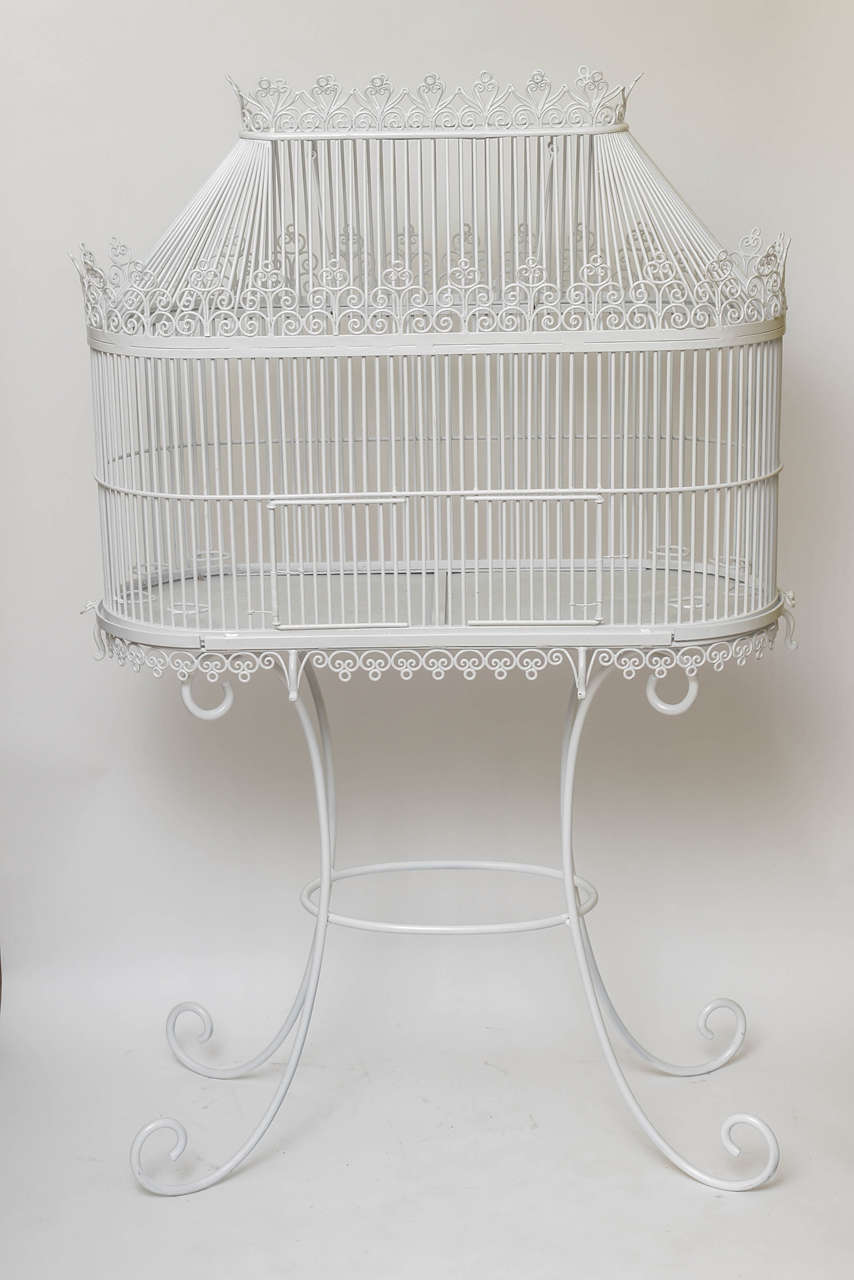 19th century birdcage of large dimensions mounted on original stand, fashioned from fine steel or iron rods, painted white with elaborate galleries.