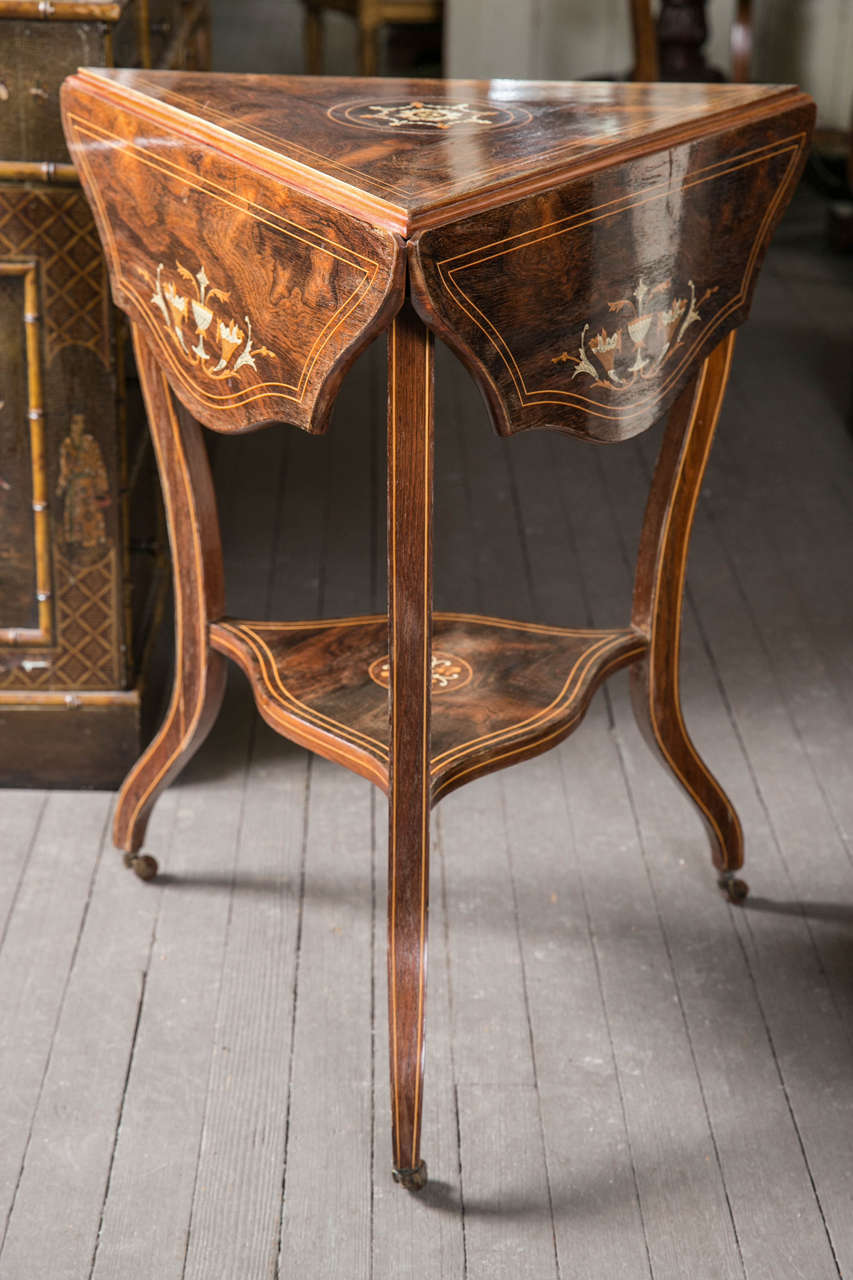 An interesting pair of table with bone inlays. Each  side (3) has drop down sides, that when fully open form an interesting  shaped top.  The inlaid legs  flow inward to an inlaid stretcher shelf and then outward to small brass casters.
A small