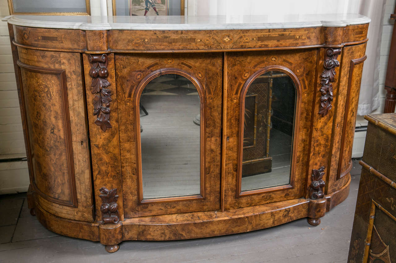 Attributed to Alexander Roux, this has a white and soft gray marble top, shaped to fit the lower case, with double concave molded edges. The case of burl walnut veneers and walnut solids.
Two swing out doors on either end. Two doors with arched