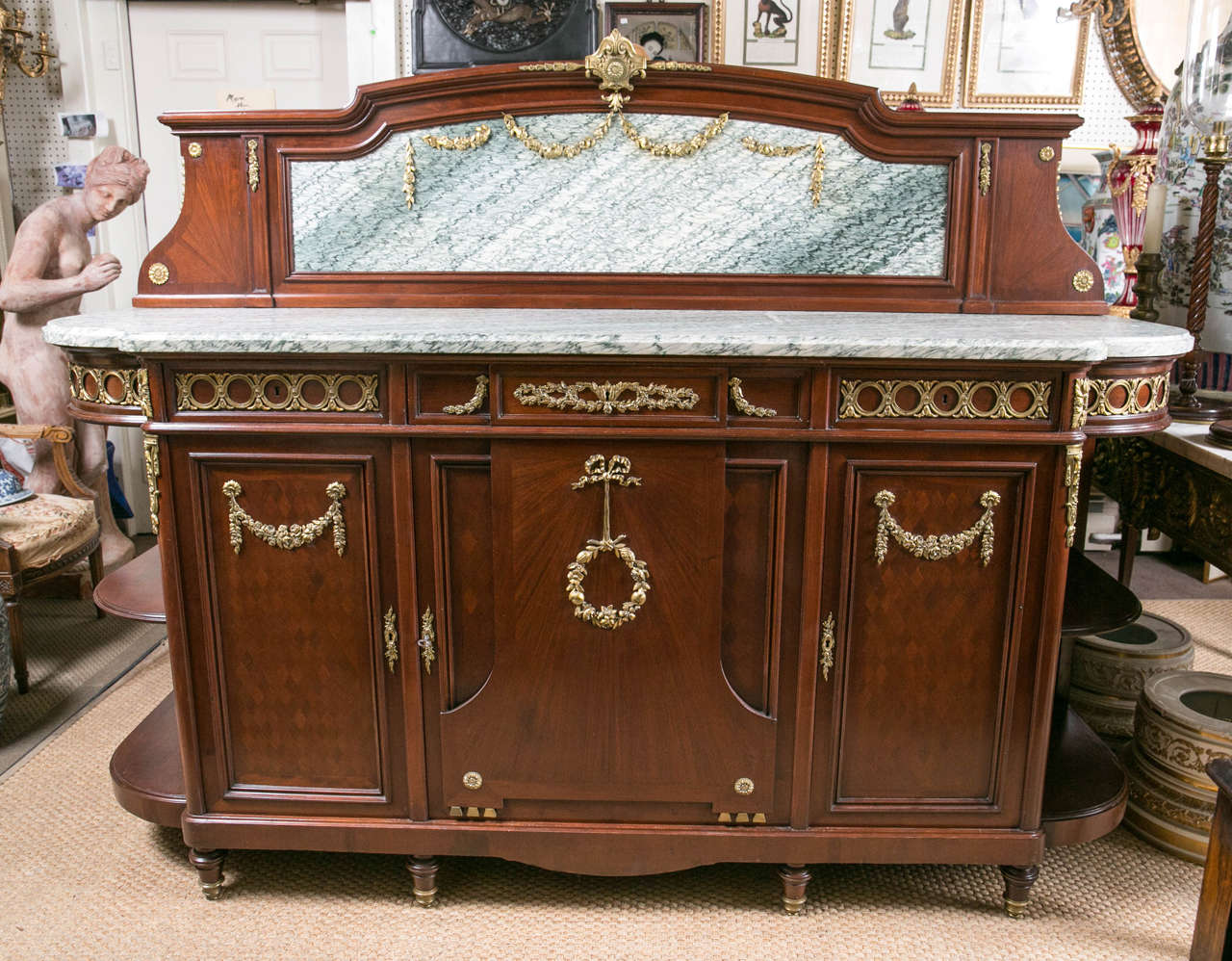 This large mahogany server has an attached shaped back with marble insert to match the top. There are original gilt bronze mounts on the mahogany frame around the marble, which also has original gilt bronze swags. The top is shaped. The marble top