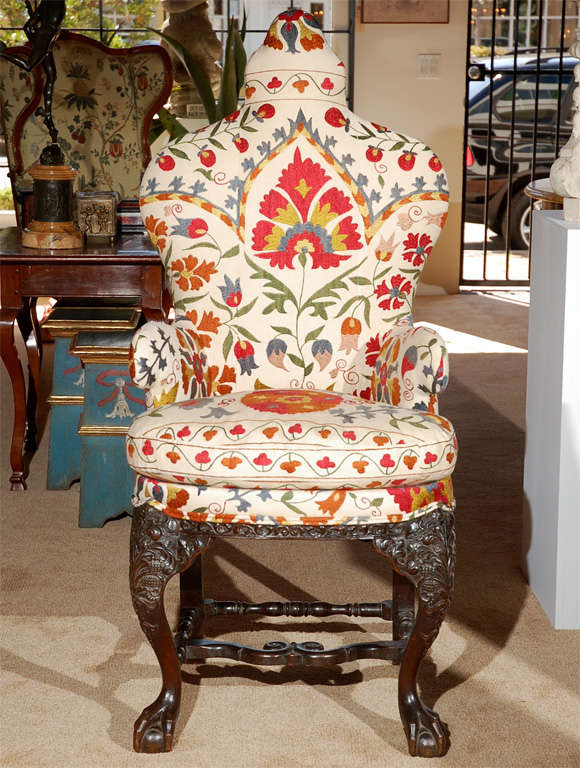 Richly hand-carved, serpentine Anglo Indian armchair above ball and claw feet and covered in vibrant Suzanni fabric.