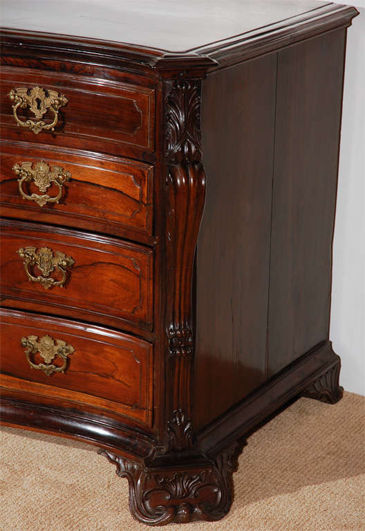 Rare, hand-carved Padouk wood commode from Portugal.  A clipped corner top surmounts richly carved, cascading side-pilasters flank five drawers. The whole on scrolled, shell-feet.