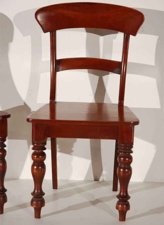 A pair of Victorian miniature wooden side chairs with turned front legs. Made of polished mahogany and likely used as samples for sales purposes.