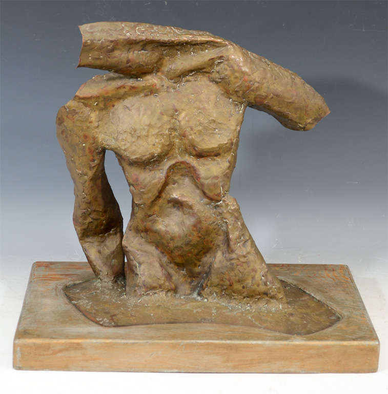 An abstract metal sculpture of a male torso mounted on a wood base. The reverse has heavy, red patination and is sign 