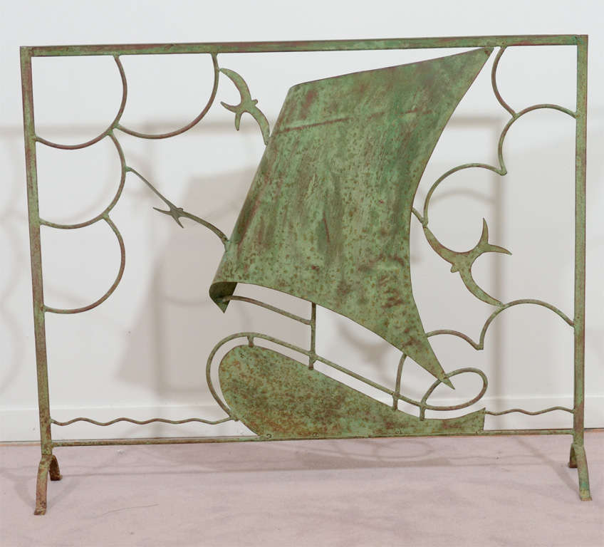 A vintage copper fire screen depicting a boat, birds, clouds and waves with an aged green patina.