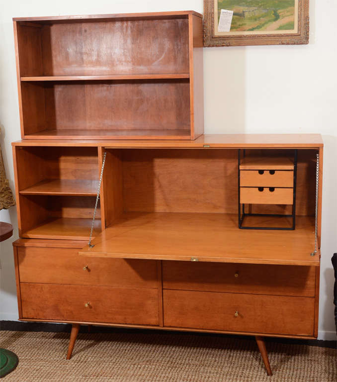 A vintage secretary by Paul McCobb for Wichendon Planner Group. The item consists of three stacked components; a lower credenza with four drawers, a secretary desk with fold down writing surface and interior storage and finally an upper book shelf.