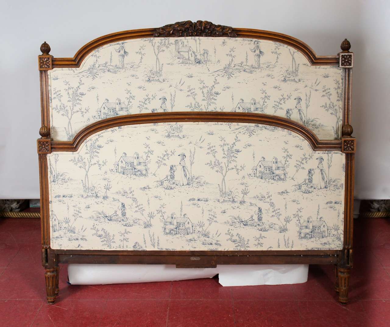 Louis XVI-style head headboard, upholstered in blue Toile de Jouy.  Solid wood.  Floral and leaf motif at center top of head board. Label reads 