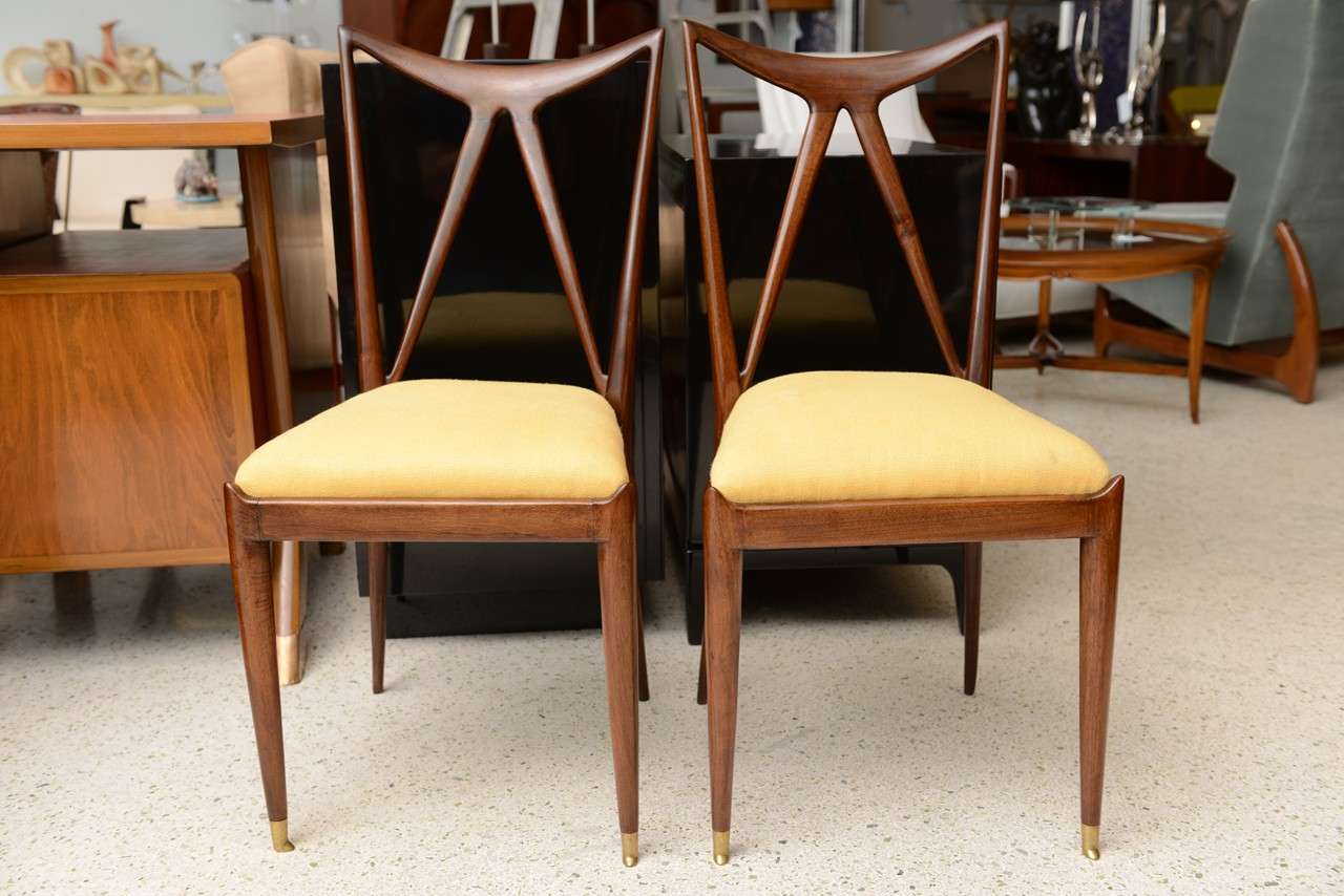 the rounded back with pierced triangular sections over a drop in upholstered seat resting on tapering legs terminating in brass caps
