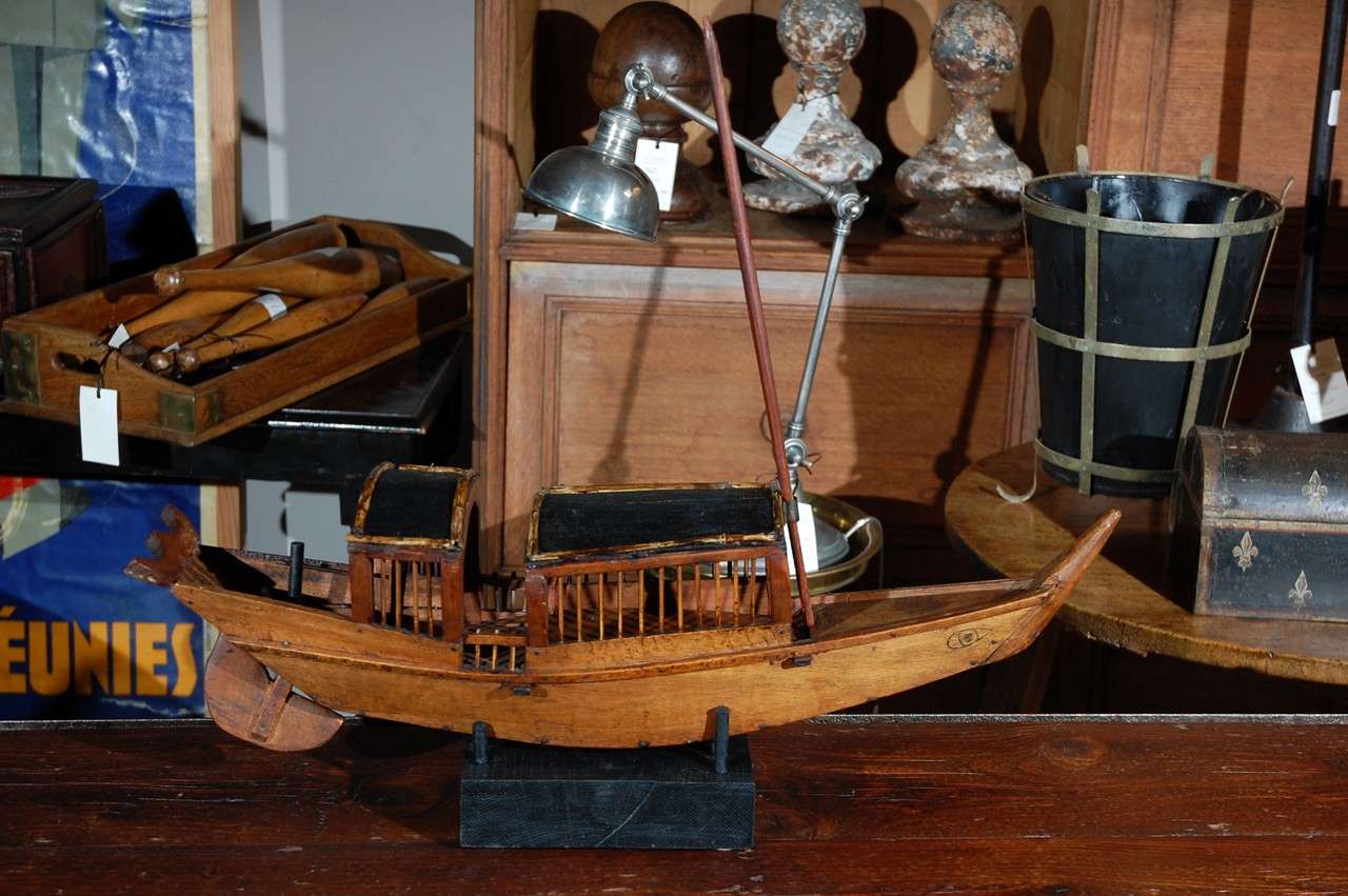 A unique carved and painted boat with a display stand.